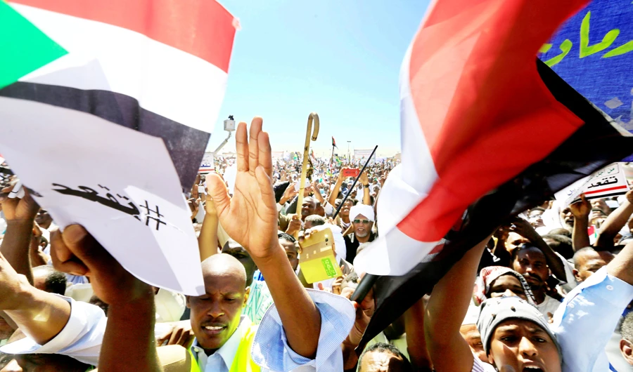 Supporters of Sudan’s President Omar Bashir wave their national flags as they chant slogans in his favor during a rally at the Green Square in Khartoum. (Reuters)