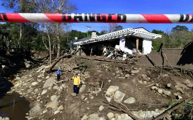 Rescue workers walk amid the debris of damaged property from mudflows carrying boulders, rocks and uprooted trees in California. (AFP)