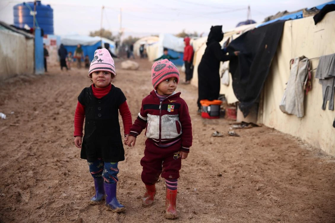 Syrian children walk together in the mud past tents at a camp for the displaced near the village of Shamarin, near the border with Turkey in the northern Aleppo province, on January 11, 2019. (File/AFP)