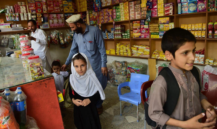 In this picture taken on September 29, 2018, Afghan refugee Ashiqullah Jan visits a shop with his children in Peshawar. (AFP / ABDUL MAJEED)