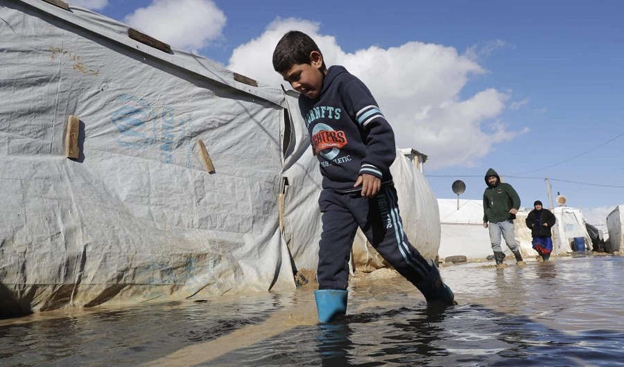 A child wades through flood waters at an informal tent settlement housing Syrian refugees following winter storms in the area of Delhamiyeh. (AFP)