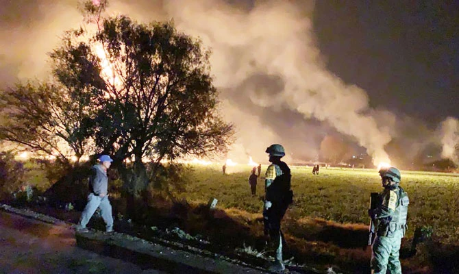 This handout photo distributed by the Mexican Secretary of National Defence (Secretaria de Defensa Nacional) shows Mexican soldiers standing guard near a fire after a leaking gas pipeline triggered a blaze in Tlahuelilpan, Hidalgo state, on January 18, 2019. (AFP)