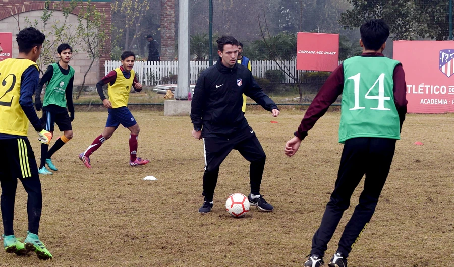 In this picture taken on January 5, 2019 Atletico De Madrid coach Javier Visea (C), 22, plays with Pakistani youths at Atletico De Madrid club's new facility for developing football in Lahore. (AFP)