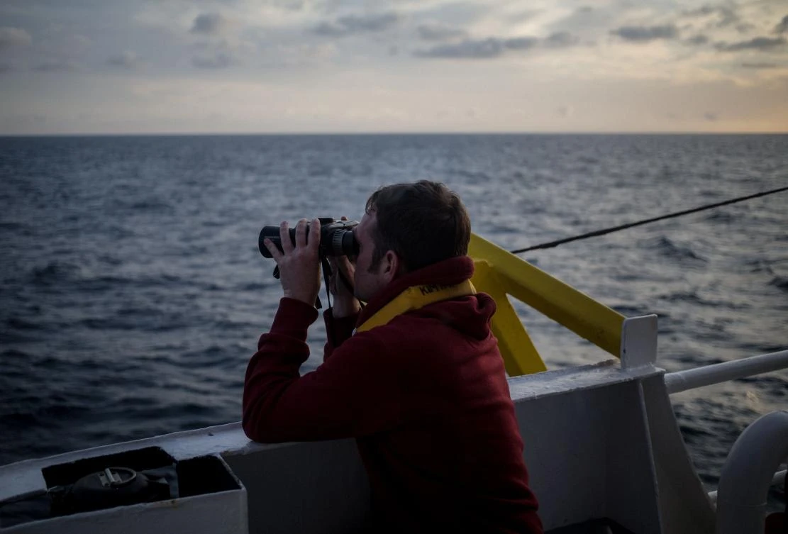 One of the crew members of the Dutch-flagged rescue vessel Sea Watch 3 keeps a watch on the sea with binoculars on January 18, 2019 during a rescue operation off Libya's coasts on January 18, 2019. (AFP)