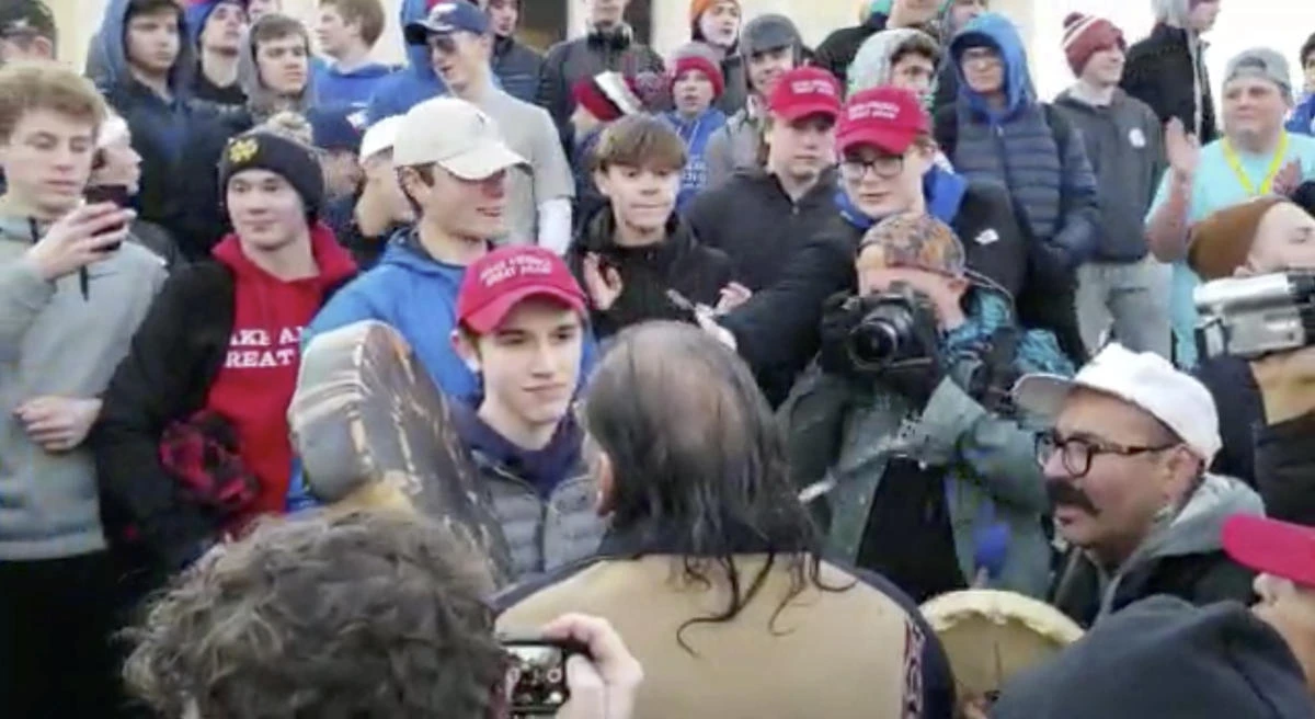 Nick Sandmann, a student from the private, all-male Covington Catholic High School in northern Kentucky, stands face to face with the Indian activist Nathan Phillips, who sings and plays a drum. (Survival Media Agency via AP)