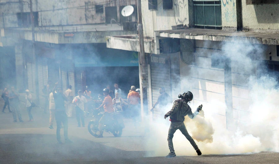 A demonstrator throws back a gas canister while clashing with security forces during a rally against Venezuelan President Nicolas Maduro's government and to commemorate the 61st anniversary of the end of the dictatorship of Marcos Perez Jimenez in Tachira, Venezuela, on January 23, 2019. (REUTERS/Carlos Eduardo Ramirez)