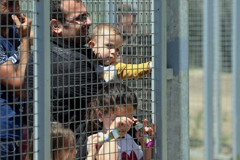 Above, migrants wait at an anti-migrant fence on Serbia-Hungary border in 2016. (AFP)