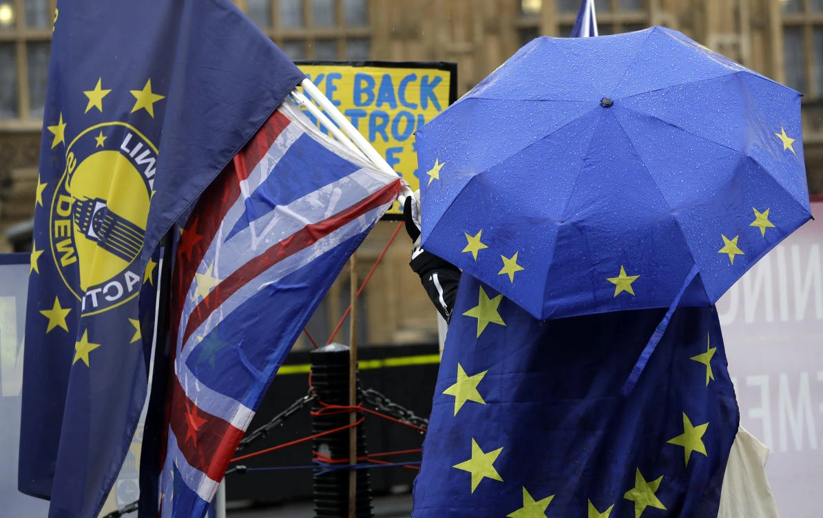 An anti-Brexit demonstrator shelters under an umbrella in the pattern of the European Union flag outside parliament in London. (AP)