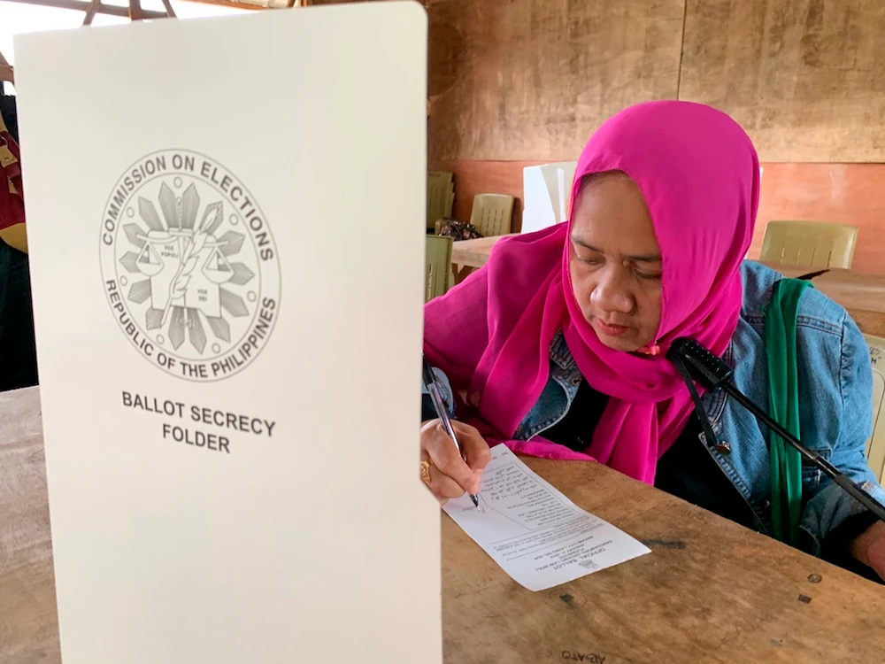 A Muslim woman writes down to vote in a referendum at the Marawi Sagonsongan elementary school-turned polling station in Marawi, Lanao del Sur province, southern Philippines, Monday, Jan. 21, 2019. (AP)