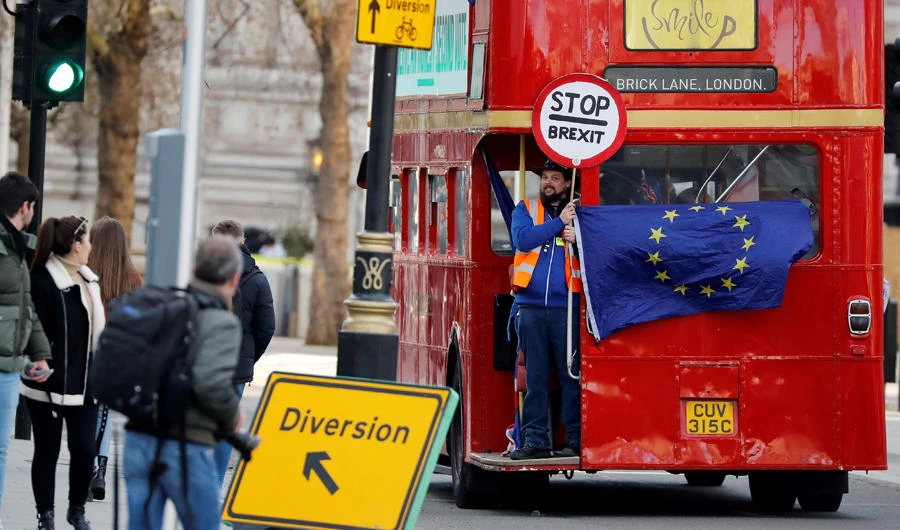An anti-Brexit activist holds a "Stop Brexit" placard and an EU flag as they travel on an old red London Routemaster bus on Whitehall, in central London on January 28, 2019. (AFP / Tolga Akmen)