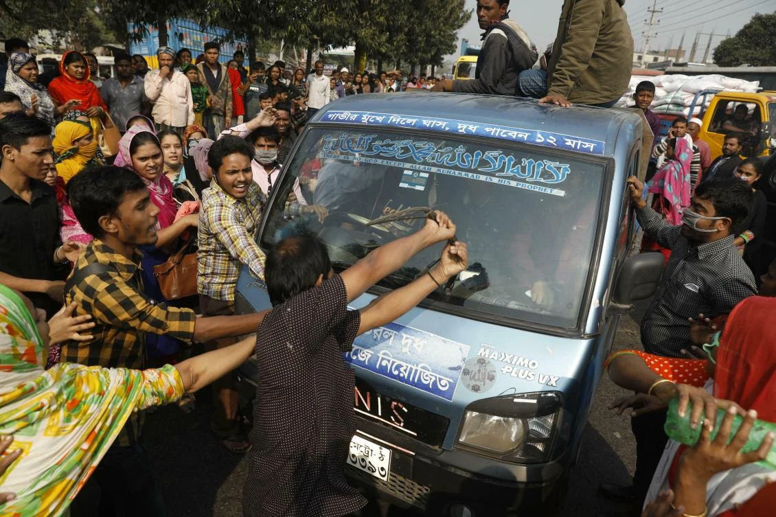 In this file photo, Bangladeshi garment workers vandalize a vehicle during a protest in Savar, on the outskirts of Dhaka, Bangladesh. (AP)