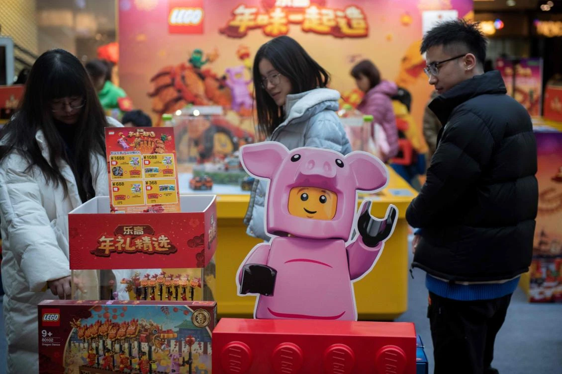 File photo shows people looking at a limited Lunar New Year package made by Danish giant toy maker Lego, featuring a Lego pig and a Lego dragon, in Beijing. (AFP)