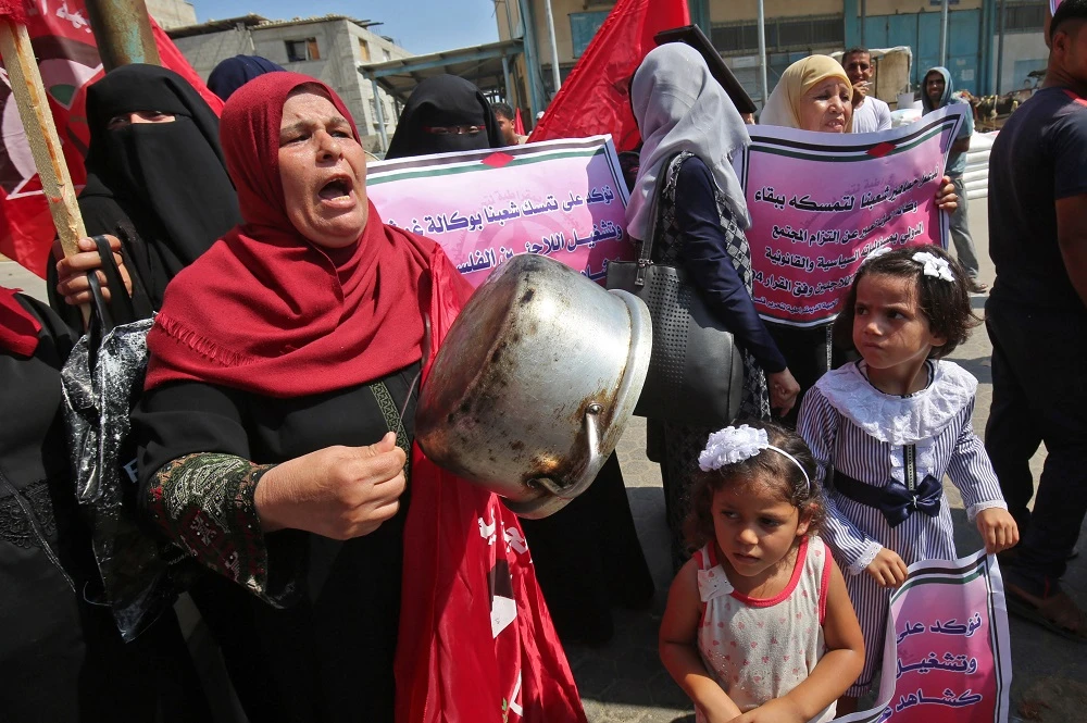 A Palestinian woman drums on a cooking pot during a protest against a US decision to cut funding to the United Nations Relief and Works Agency (UNRWA), outside an aid distribution center, in Khan Yunis in the southern Gaza Strip. (File photo/AFP)