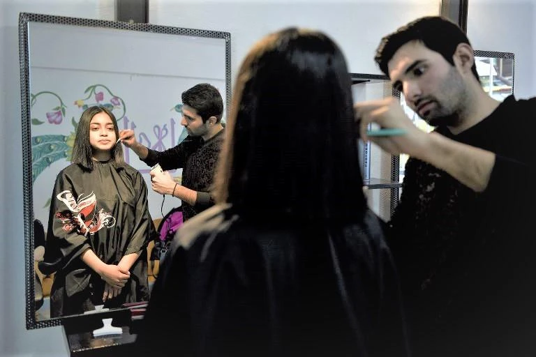 Pakistani Manassif Raza with one of the first customers in his new hair salon at Athens’ Agios Panteleimonas, home to many immigrants and refugees. (AFP)