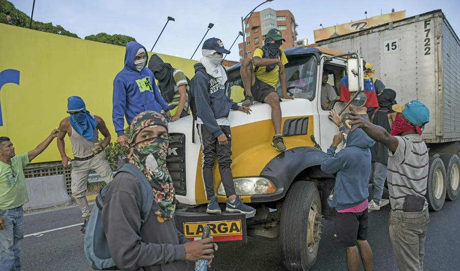 Anti-government protesters stop a truck while blocking a highway with a small group of demonstrators who were returning from a peaceful demonstration called by self-declared interim president Juan Guaido to demand the resignation of President Nicolas Maduro, in Caracas, Venezuela, on Feb. 2, 2019. (AP Photo/Rodrigo Abd)