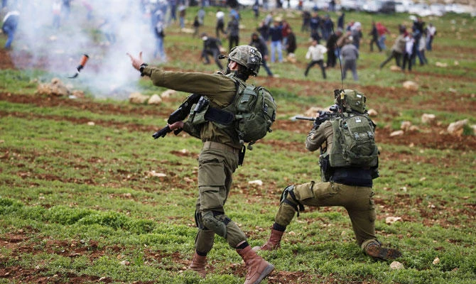 An Israeli soldier throws a tear gas canister at Palestinian demonstrators during a protest against Jewish settlements, in al-Mughayyir village near Ramallah, in the Israeli-occupied West Bank, on February 1, 2019. (AFP)