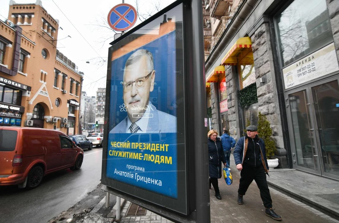 People walk past a campaign poster of the Ukrainian presidential candidate Anatoliy Grytsenko reading the slogan "Honest President will serve people" in Kiev, on February 4, 2019. (AFP)