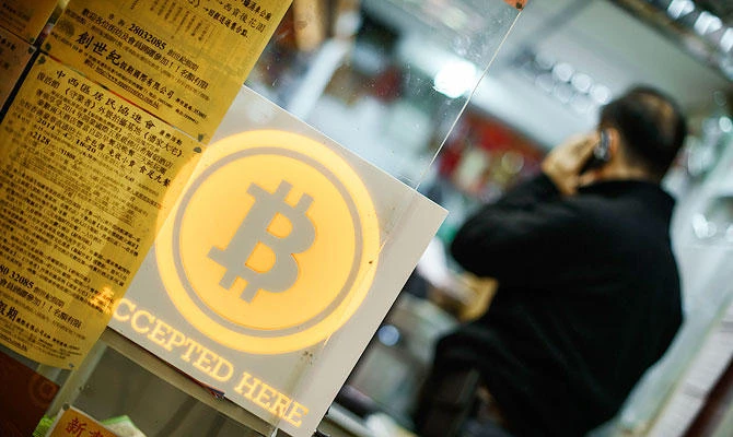 This file picture taken on February 28, 2014 shows a man talking on a mobile phone in a shop displaying a bitcoin sign during the opening ceremony of the first bitcoin retail shop in Hong Kong. (AFP)