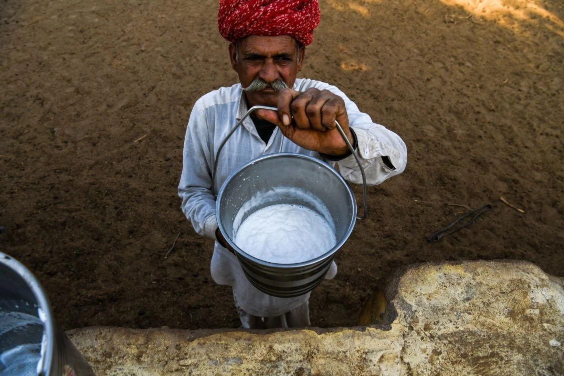 A farmer holds up fresh camel milk at a camel research farm in Bikaner in India's western state of Rajasthan. (AFP)