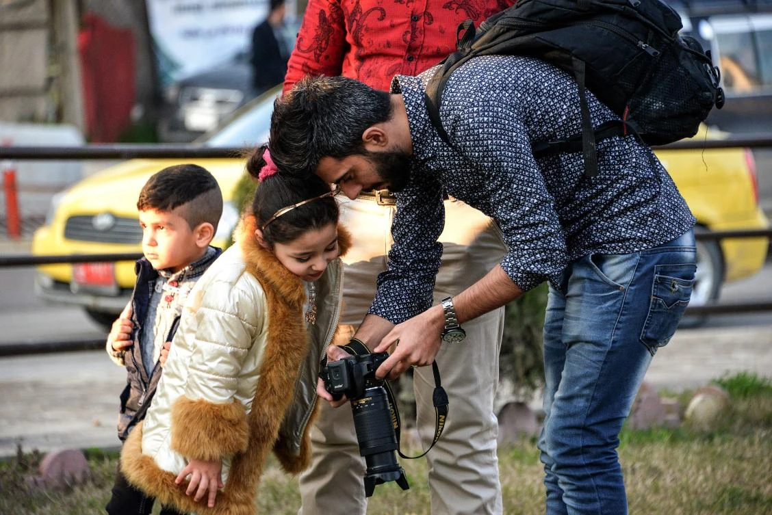 A photographer shows a girl a picture taken on his camera at Nafoura square in the Al-Zuhur neighborhood of Mosul. Residents have been hiring local photographers to capture mementos of their city’s darkest days. (AFP)