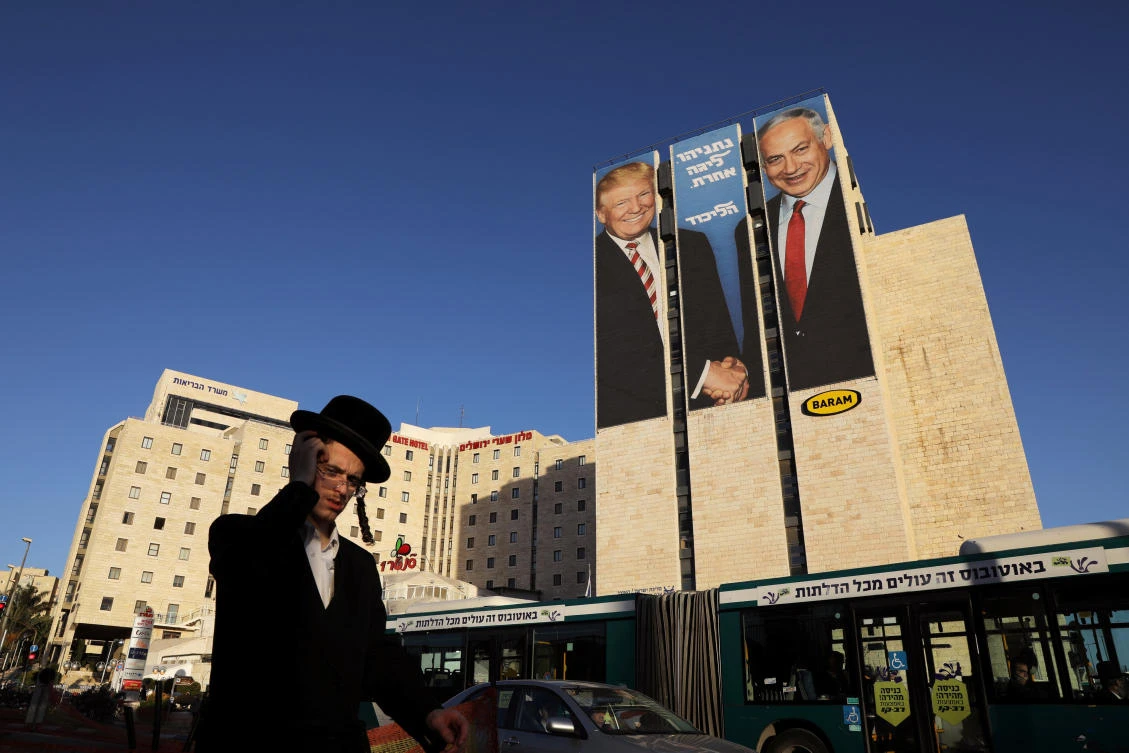 A man walks past a Likud election campaign billboard, depicting US President Donald Trump shaking hands with Israeli Prime Minister Benjamin Netanyahu, in Jerusalem February 4, 2019. (Reuters)
