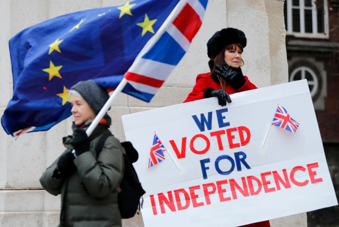 In this file photo taken on January 21, 2019 A pro-Brexit activist (R) holds a placard reading "We Voted For Independence" as an anti-brexit campaigner waves an European Union and a Union flag. (AFP)