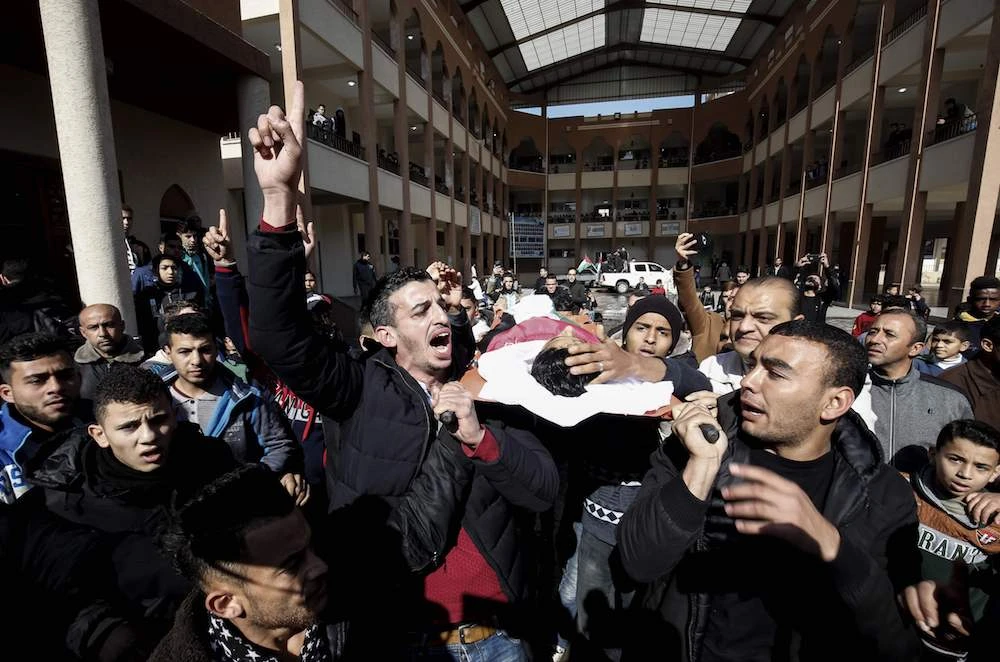 Mourners carry the body of Hassan Shalabi, 14, through his school in Khan Yunis in the southern Gaza Strip. Two Palestinian teenagers were killed by Israeli fire yesterday, during clashes along the Gaza border. (AFP)