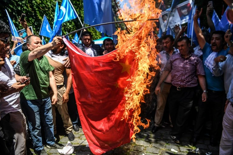 Uighur Muslims supporters and Turkish nationals burn the Chinese flag in front of the Chinese consulate in Istanbul on July 5, 2018. (AFP)