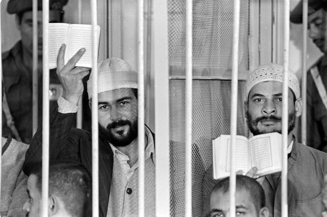 In this Nov. 30, 1981 file photograph, Khalid al-Islambouli, left, and Abdel Hamid Abdel Aal hold up open Qurans during the second day of their trial in Cairo, Egypt, Monday, Nov. 30, 1981. (AP)