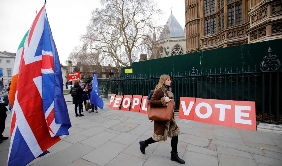 In this file photo taken on January 21, 2019 A pedestrian walks pas a placard reading "People's Vote" as Brexit activists demonstrate outside of the Houses of Parliament in central London, while Britain's Prime Minister Theresa May makes a statement to the House of Commons on changes to her Brexit withdrawal agreement. (AFP file)