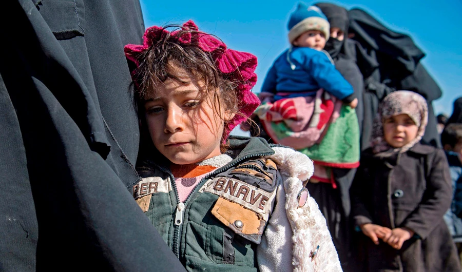 Women and children stand in a field after they fled from the Baghouz area in the eastern Syrian province of Deir Ezzor on Tuesday. (AFP)