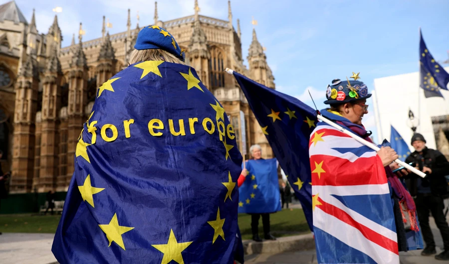 Anti-Brexit pro-EU demonstrators stand wrapped in EU and Union Flags outside the Houses of Parliament in London on Feb. 13, 2019. (AFP)