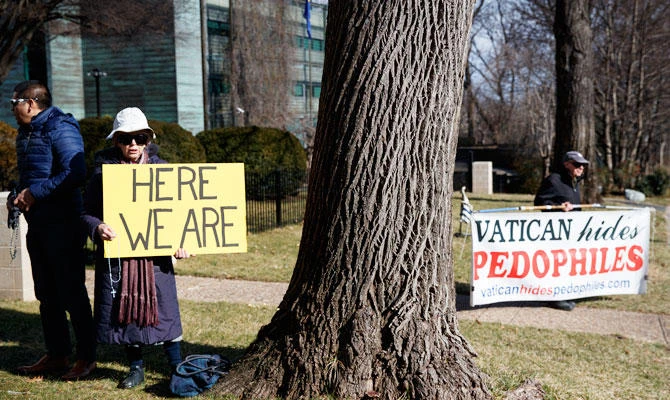 A group with Catholic Laity for Orthodox Bishops and Reform, left of the tree, gathers to pray the rosary, as John Wojnowski holds a sign at right that reads "Vatican hides Pedophiles" outside the Apostolic Nunciature of the Holy See in Washington, Saturday, Feb. 16, 2019. (AP)