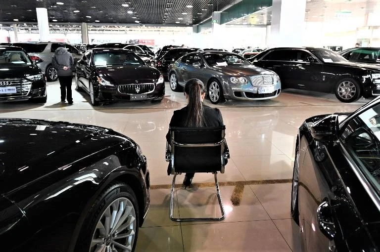 A sales representative waiting for customers in a luxury car showroom in Beijing. Car sales dropped to 2.37 million vehicles last month, mirroring declines during previous months. (AFP)