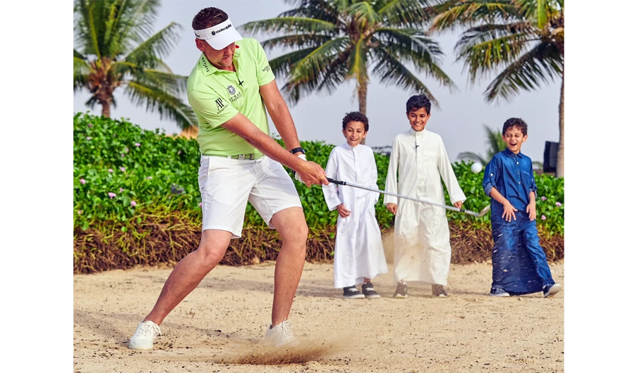 Ryder Cup star Ian Poulter shows off his bunker skills for local KAEC youngsters.