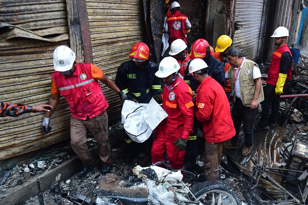 Bangladeshi rescuers carry the body of a victim from one of the buildings razed by a fire in Dhaka on Thursday. (AFP / Munir Uz Zaman)