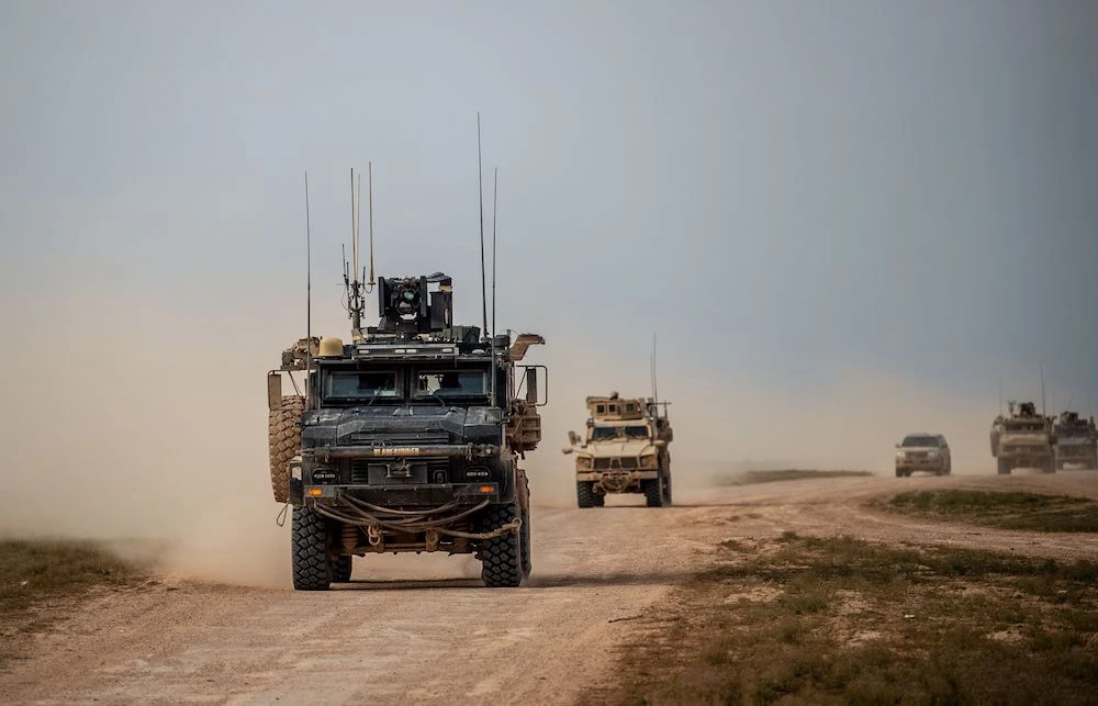 A picture taken on February 21, 2019 shows vehicles belonging to the US-backed coalition as they drive down a road in Syria's northern Deir Ezzor province. (AFP)
