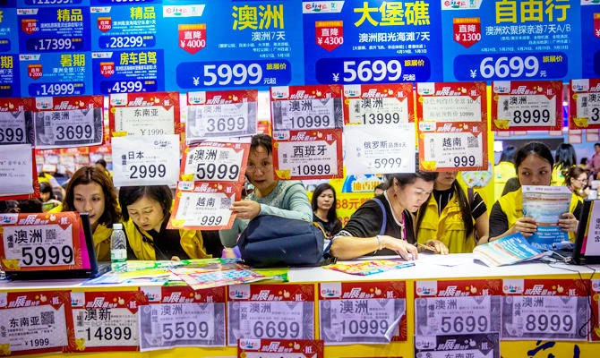 In this March 3, 2018, photo, people check on travel packages offered by travel agencies during the Guangzhou International Travel Fair in Guangzhou in south China's Guangdong province. (AP)