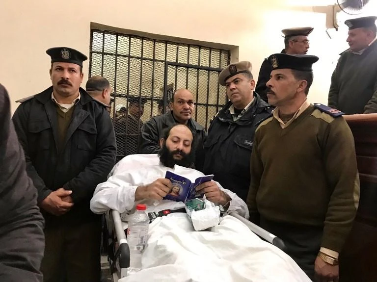Egyptian monk Philotheos, center, lies on a stretcher during his and monk Isaiah’s trial in Damanhur. The two were sentenced to death over the murder of a bishop. (AFP)