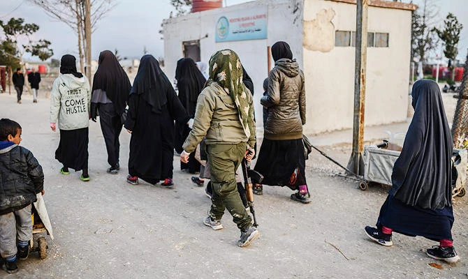 In this file photo taken on February 17, 2019 veiled women, reportedly wives and members of the Daesh, walk under the supervision of a female fighter from the Syrian Democratic Forces (SDF) at al-Hol camp in al-Hasakeh governorate in northeastern Syria. (AFP)