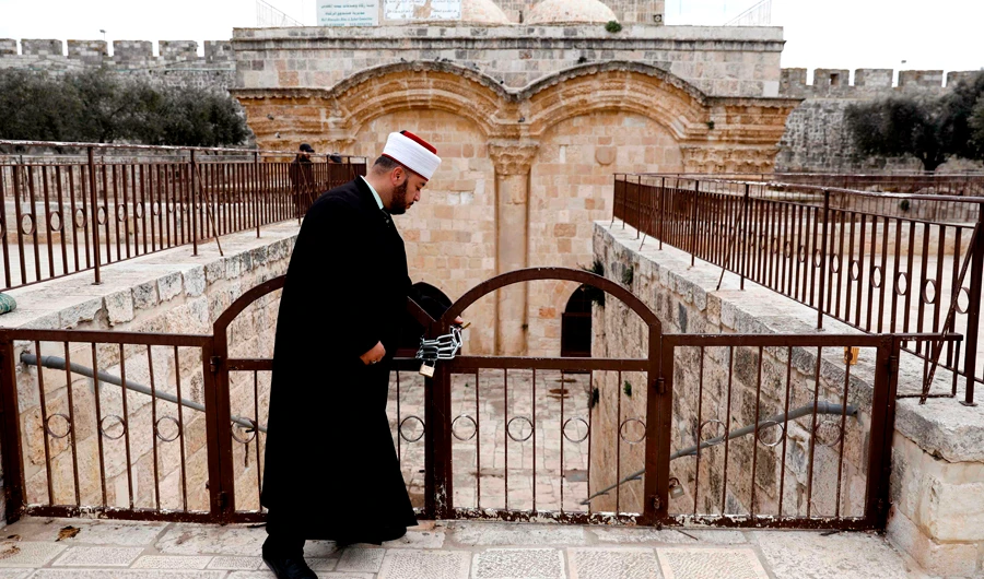 A cleric checks a gate at the Al-Aqsa Mosque compound in Jerusalem. (AFP)