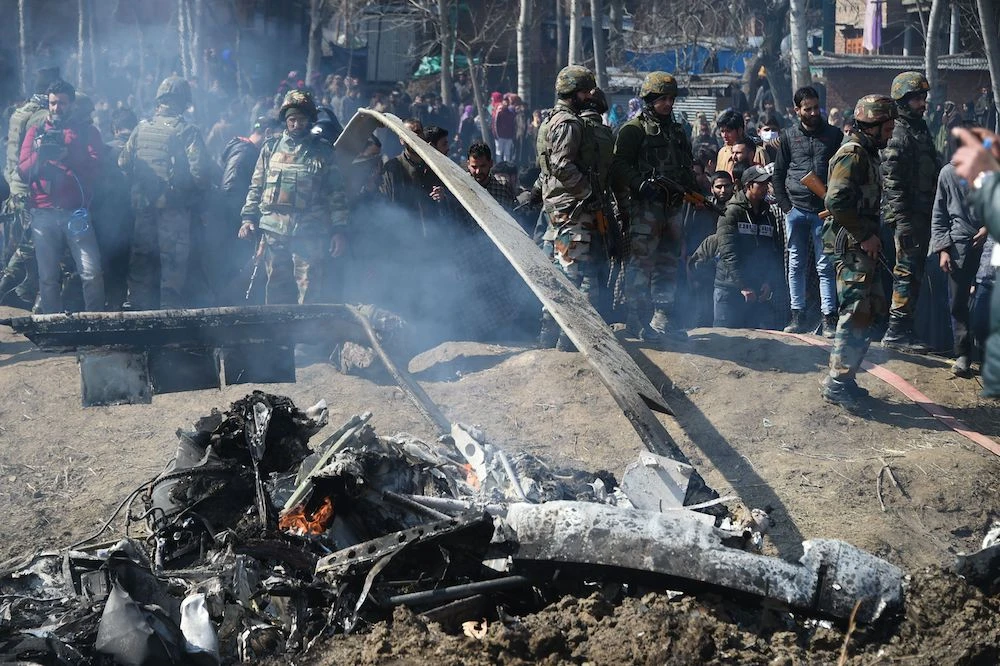 Indian soldiers and Kashmiri onlookers stand near the remains of an Indian Air Force helicopter after it crashed in Budgam district, outside Srinagar on Wednesday (AFP)