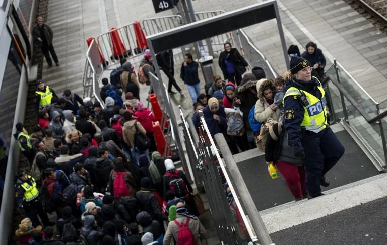 Police organize a line of refugees on the stairway leading up from trains arriving at the Hyllie train station in Sweden. A person has been arrested on suspicion of spying on refugees who fled to Sweden. (File/AFP)