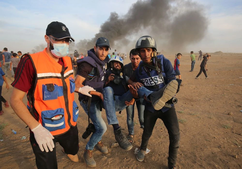 Palestinian paramedics and journalists carry a wounded fellow journalist during clashes with Israeli forces in Gaza. (AFP)