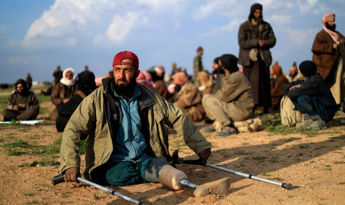 An amputated man looks on as men suspected of being Daesh fighters wait to be searched by members of the Kurdish-led Syrian Democratic Forces (SDF) after leaving the Daesh group's last holdout of Baghouz, in Syria's northern Deir Ezzor province on February 22, 2019. (AFP / Delil Souleiman)