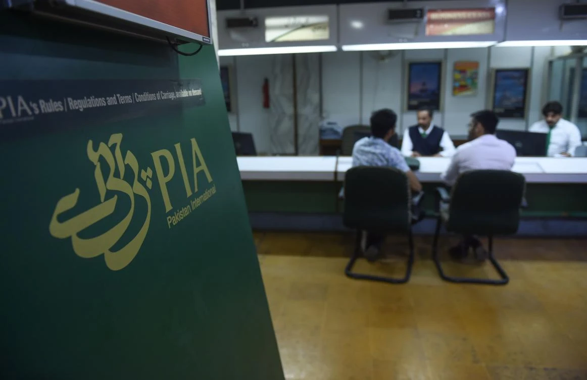Staff of Pakistan International Airlines (PIA) talk with passengers at a PIA office in Karachi on February 27, 2019.(AFP)