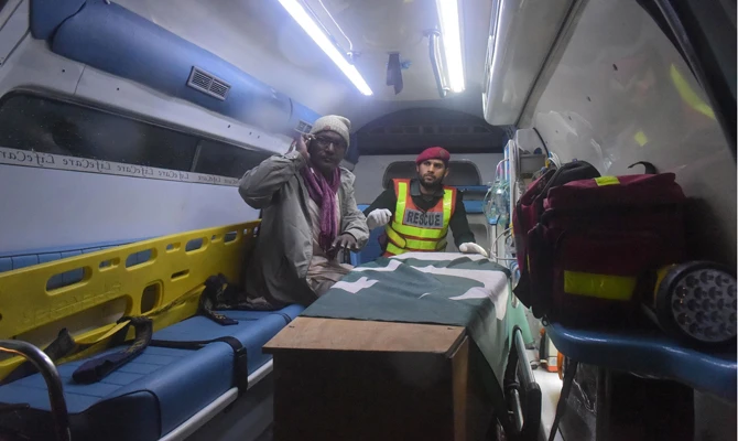 Shahzad (L), brother of killed Pakistani prisoner Shakir Ullah, sits next to his sibling's coffin in an ambulance after the body was returned by Indian authorities on the India-Pakistan Wagah border on March 2, 2019. (AFP / ARIF ALI)