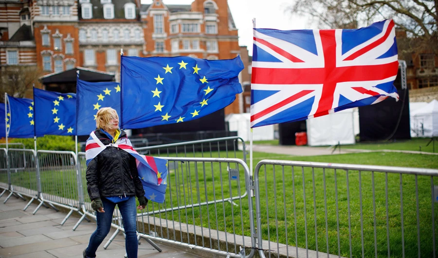 An anti-Brexit protester draped in a composite if the EU and Union flag walks past more flags outside the Houses of Parliament in London on March 4, 2019. (AFP)
