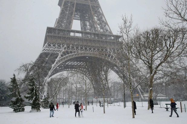People stroll along the snow-covered Champ de Mars on February 9, 2019. (AP)