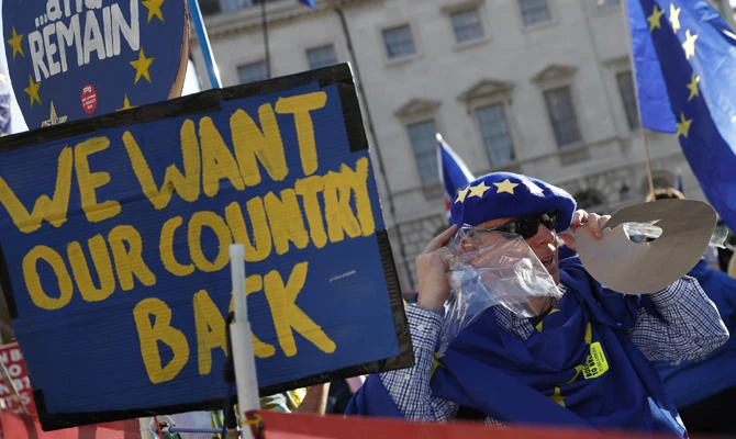 A European Union supporter tries on a new beret which shows the starts of the EU flag, as he take part in a demonstration outside the Palace of Westminster in London, . (AP Photo/Alastair Grant)